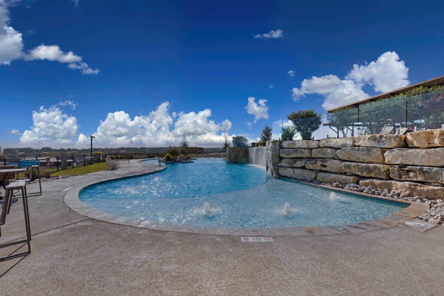 Resort-style pool with a rock waterfall and glass railing
